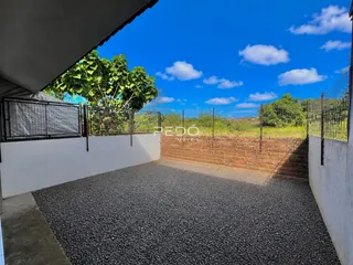 Área externa com piso de cascalho e cerca de ferro.