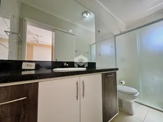 Foto de um banheiro com bancada escura e armários brancos.