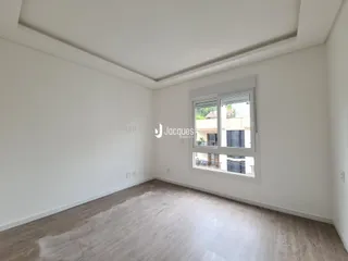 Imagem de um cômodo interno com piso de madeira clara e janela.