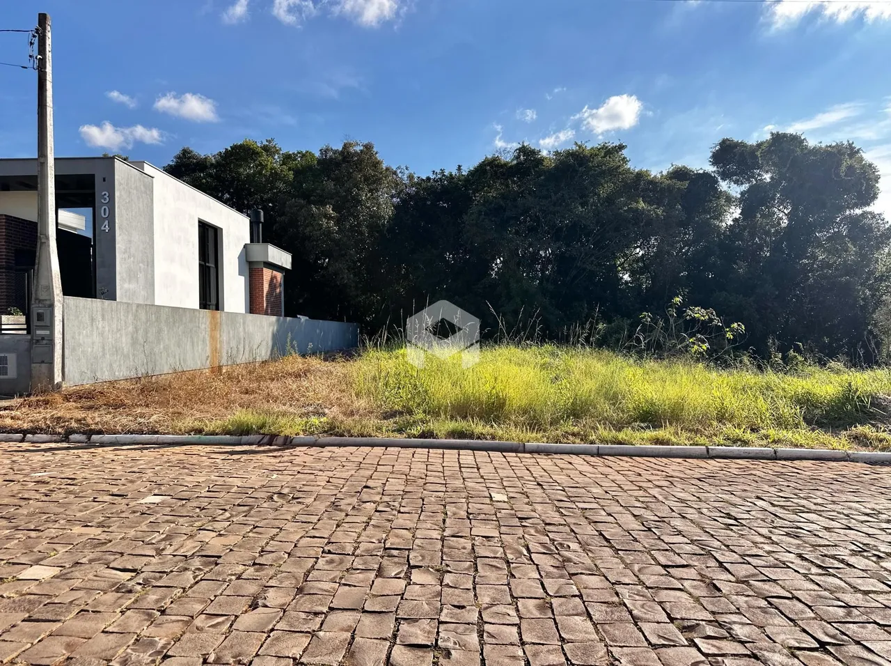 Vista da fachada de uma propriedade em Lajeado, Brasil, com vegetação alta no quintal.