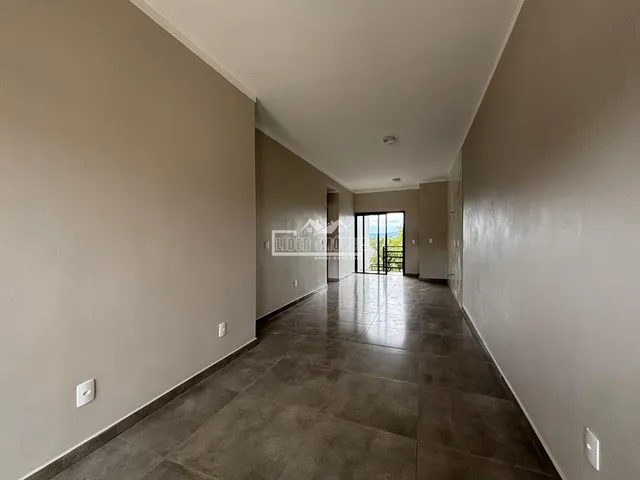 Corredor interno de uma residência com piso escuro e paredes claras.