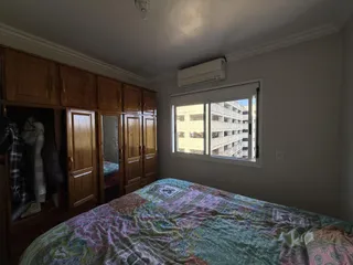 Quarto com armários de madeira e cama coberta com edredom estampado.