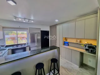 Vista da cozinha moderna com bancada escura e armários claros.