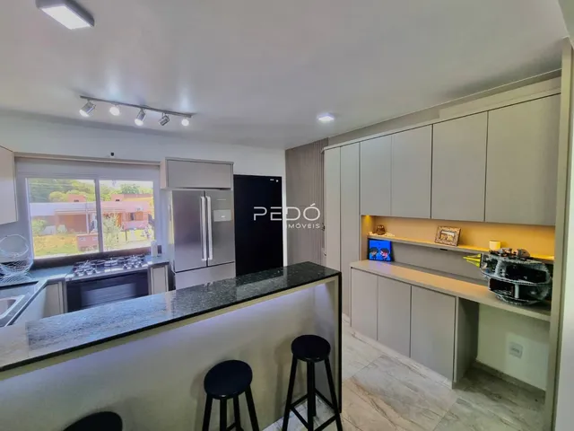 Vista da cozinha moderna com bancada escura e armários claros.