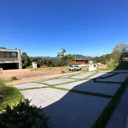 Área externa pavimentada com paisagismo verde.