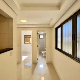 Corredor interno com paredes brancas e piso claro.