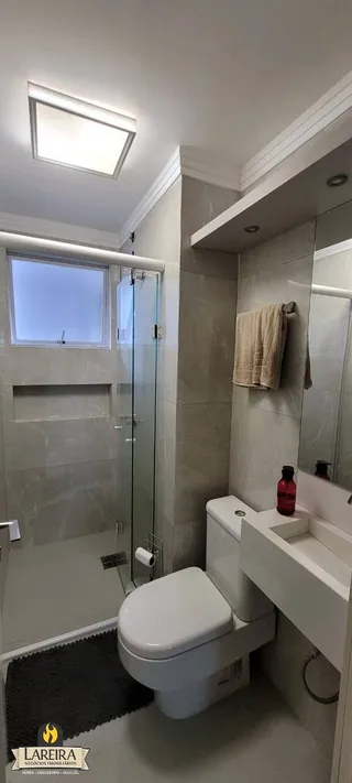 Foto de um banheiro interno com box de vidro e vaso sanitário.