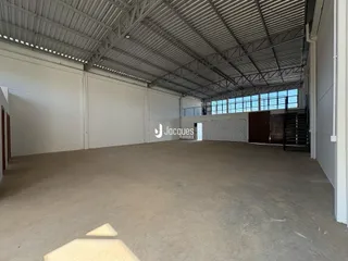 Espaço amplo com piso de concreto e estrutura metálica.