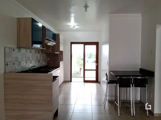 Interior de uma cozinha com armários de madeira e piso de cerâmica.