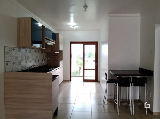 Interior de uma cozinha com armários de madeira e piso de cerâmica.