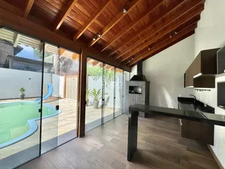 Ambiente interno com piso de madeira e portas de vidro que dão acesso a uma área externa com piscina.