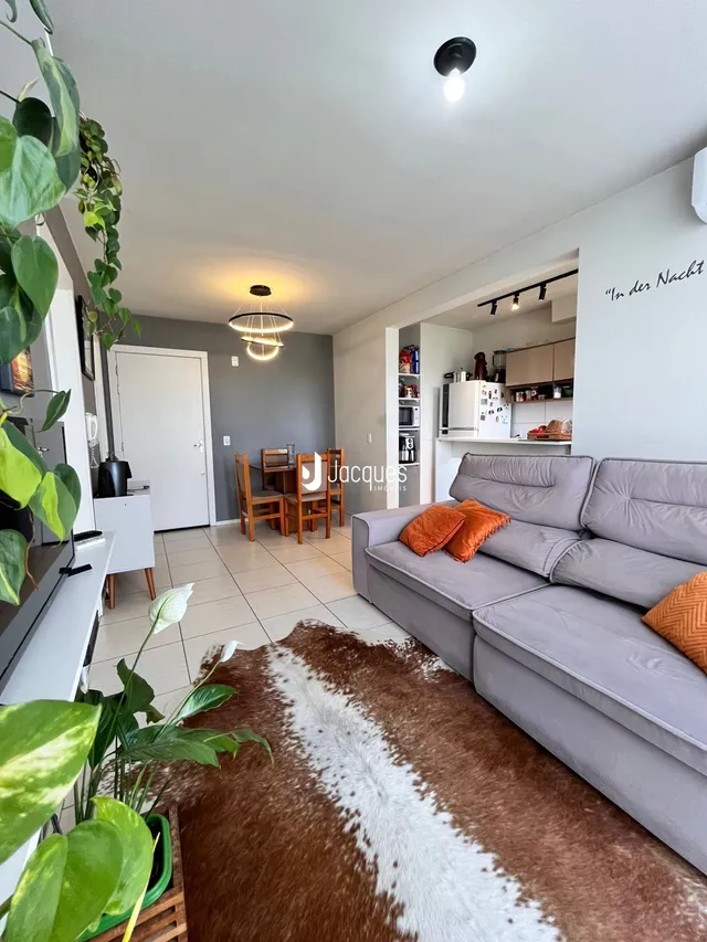 Sala de estar com sofá cinza e piso de cerâmica em um imóvel no Brasil.