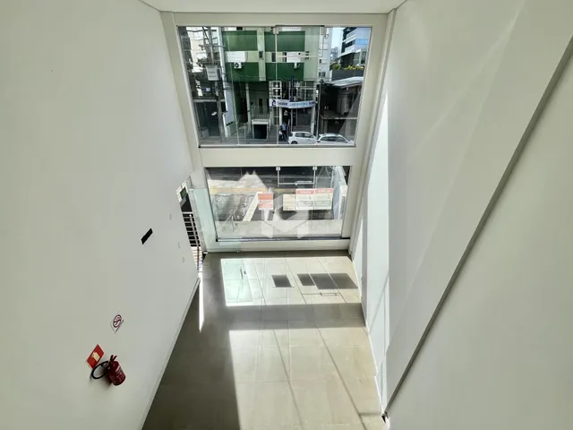 Corredor interno com grandes janelas que dão vista para o exterior.