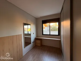 Vista interna de um corredor com piso de madeira e armários em um imóvel em Lajeado.