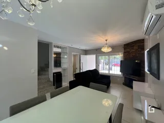 Sala de estar moderna com decoração clara e vista para o exterior.
