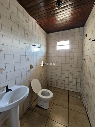 Foto de um banheiro com azulejos brancos e teto de madeira.