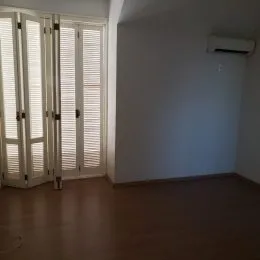 Ambiente interno com janelas cobertas por persianas e piso de madeira.