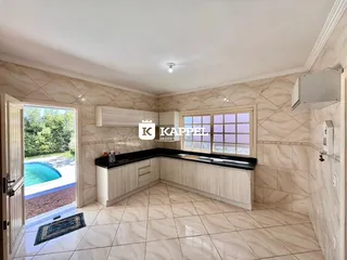 Foto de uma cozinha com armários brancos e piso de porcelanato em um imóvel.