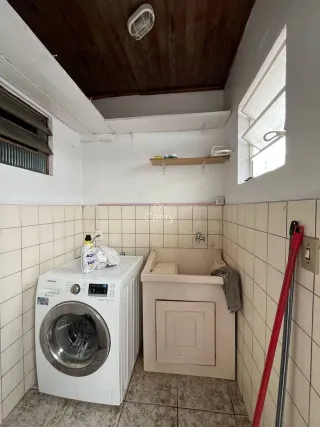 Foto do ambiente de lavanderia com máquina de lavar e bancada de apoio.