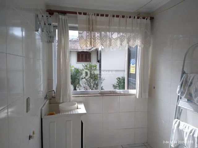 Interior de um banheiro com paredes brancas e janela com cortinas.