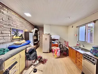 Interior de uma sala com piso de madeira e parede de tijolos expostos.