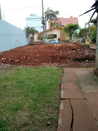 Vista externa de um terreno com terra exposta e gramado na frente de uma residência.