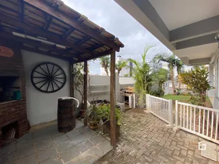 Vista de um pátio externo com muro branco e vegetação.