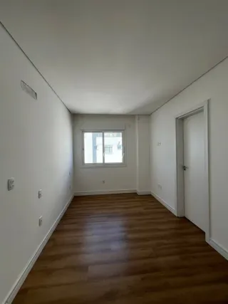 Foto interna de um ambiente com piso de madeira e paredes brancas.