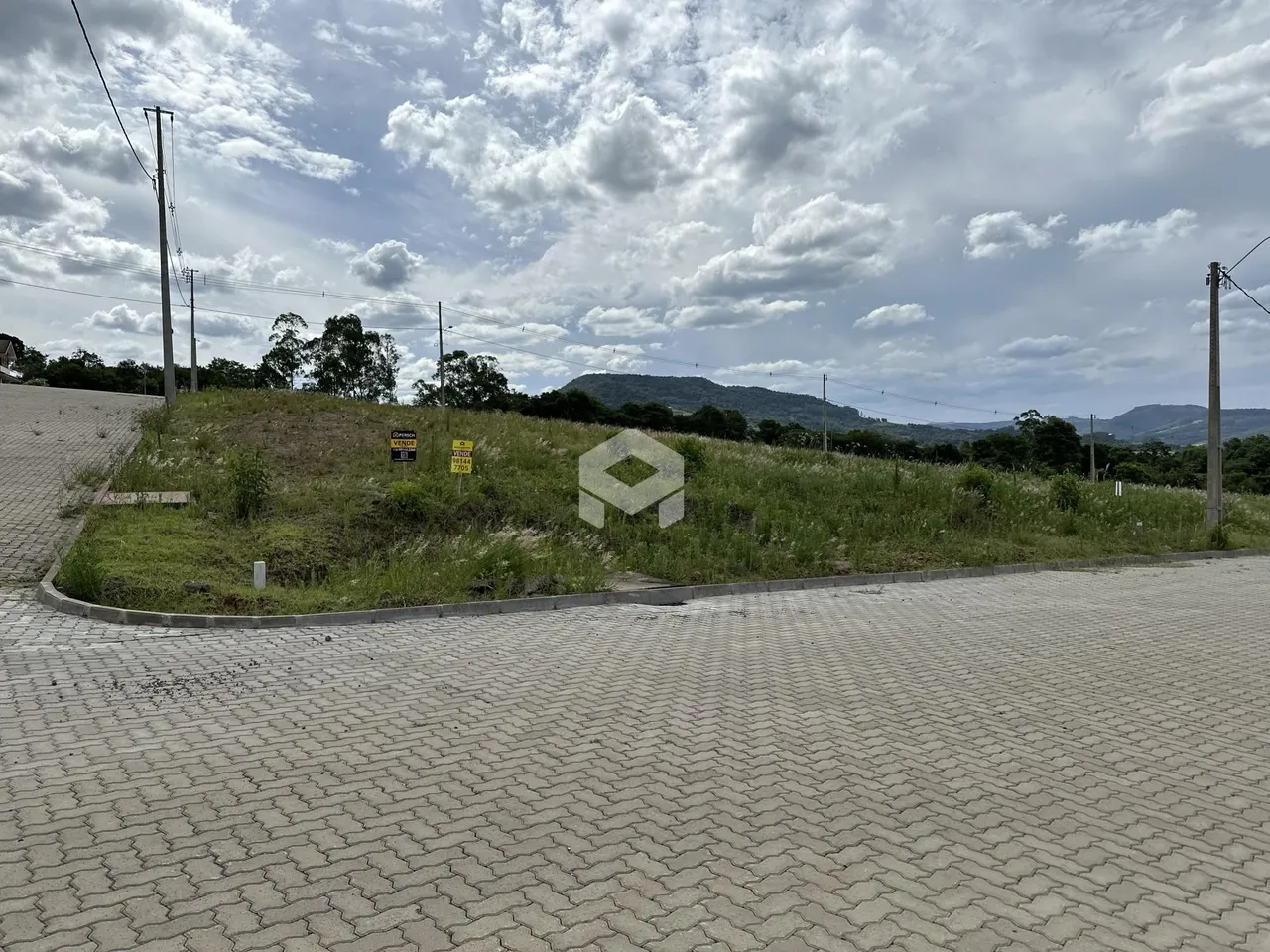 Vista de um terreno com vegetação e colinas ao fundo.