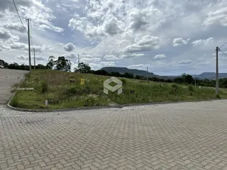 Vista de um terreno com vegetação e colinas ao fundo.
