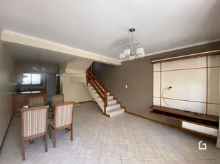 Sala com piso de cerâmica e escadaria de madeira.