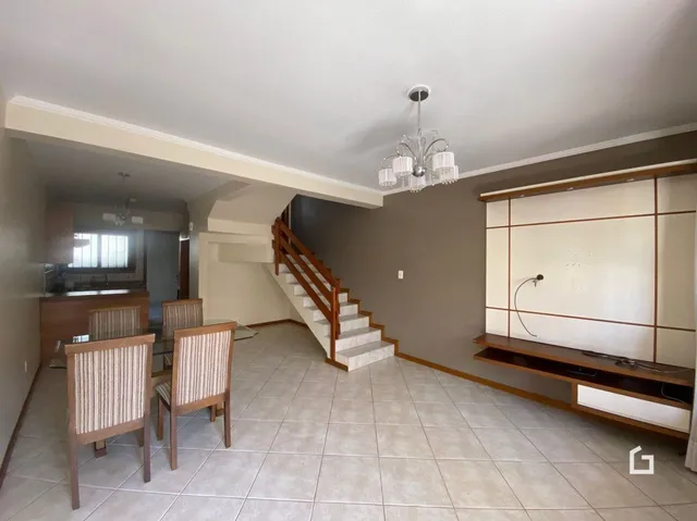 Sala com piso de cerâmica e escadaria de madeira.