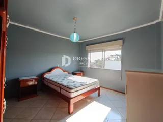 Quarto com cama de madeira e janela em um imóvel no Brasil.