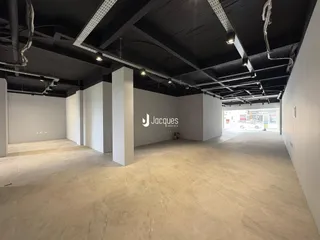 Imagem de um espaço interno amplo com piso claro e estrutura de teto exposta.