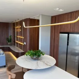 Sala de estar com painel de madeira e elemento arquitetônico dourado.