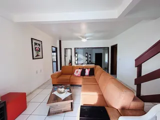 Sala de estar com sofá laranja e mesa de centro em um imóvel no Brasil.