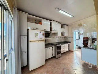 Vista da cozinha com armários brancos e piso de cerâmica.
