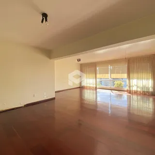 Sala ampla com piso de madeira polida e grandes janelas.