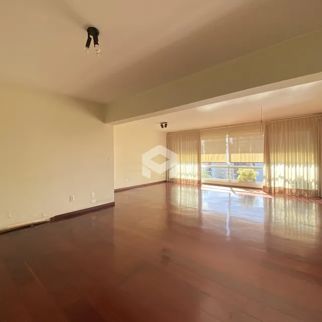 Sala ampla com piso de madeira polida e grandes janelas.