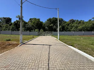 Vista da entrada de uma propriedade com um caminho pavimentado e cerca no fundo.