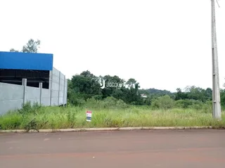 A foto mostra a fachada de uma estrutura industrial com vegetação ao fundo.