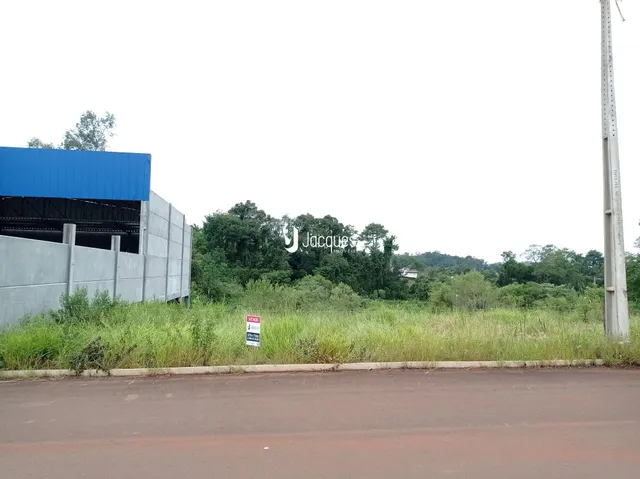 A foto mostra a fachada de uma estrutura industrial com vegetação ao fundo.