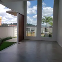 Ambiente interno com piso de concreto e grande abertura para o exterior.