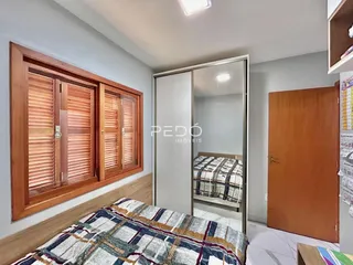 Quarto com janela de madeira e cama no interior de uma residência.