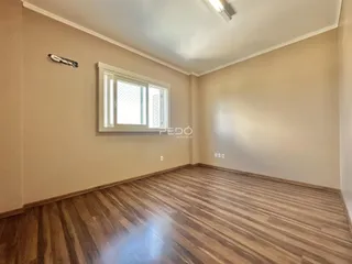 Sala de estar com piso de madeira e janela em um imóvel no Brasil.