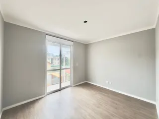 Esta é uma sala ampla com piso de madeira clara e porta de vidro que dá para o exterior.