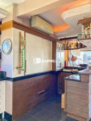 Cozinha com armários de madeira e bancadas escuras, apresentando uma área de bar.
