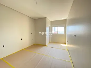 Vista interna de um cômodo com paredes brancas e piso em preparação.