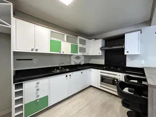 Foto de uma cozinha moderna com armários brancos e bancadas escuras.