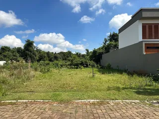 Vista externa de um terreno gramado com vegetação densa ao fundo.